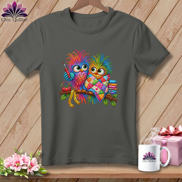A charcoal gray crewneck t-shirt featuring a colorful graphic of two whimsical owls perched on a branch.