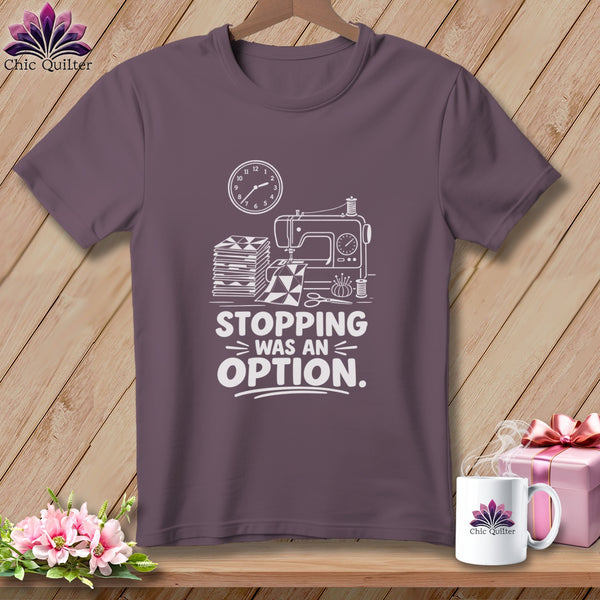 Purple t-shirt with sewing machine, fabric, and clock graphic and "Stopping Was An Option" text.