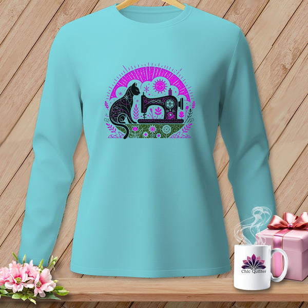 Light blue long-sleeved shirt with a black cat and sewing machine graphic, displayed on a wooden background.