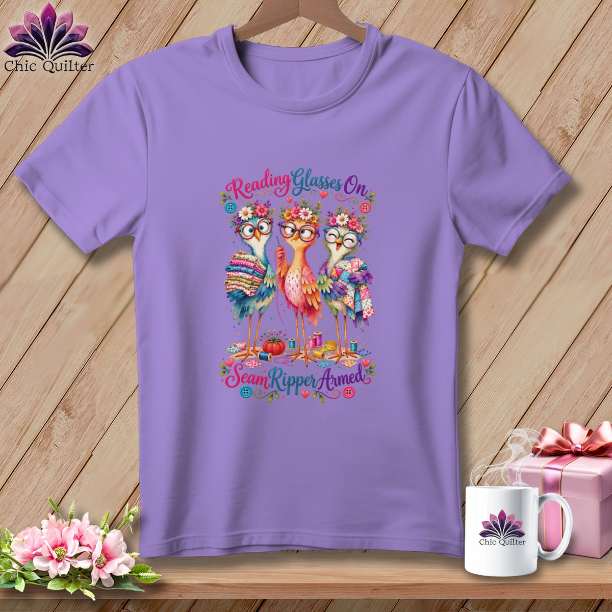Light purple t-shirt featuring a cartoon design of three birds wearing glasses and floral crowns with the text Reading Glasses On Seam Ripper Armed.