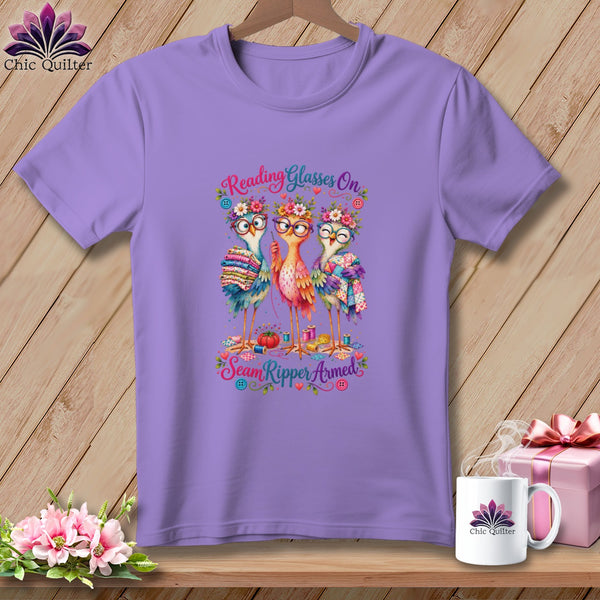 Light purple t-shirt featuring a cartoon design of three birds wearing glasses and floral crowns with the text Reading Glasses On Seam Ripper Armed.