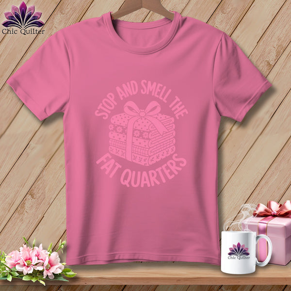 A pink t-shirt with the text Stop And Smell The Fat Quarters and an illustration of folded fabric.