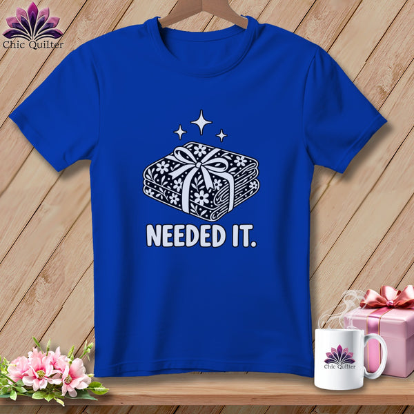 Royal blue t-shirt with a graphic of stacked fabric rolls tied with a bow and the text "NEEDED IT."