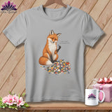 Grey t-shirt with a fox holding a quilt square and surrounded by fabric scraps.