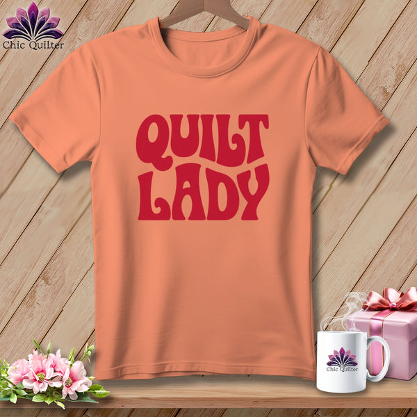 Peach t-shirt with "Quilt Lady" text in red, with a mug and gift box.