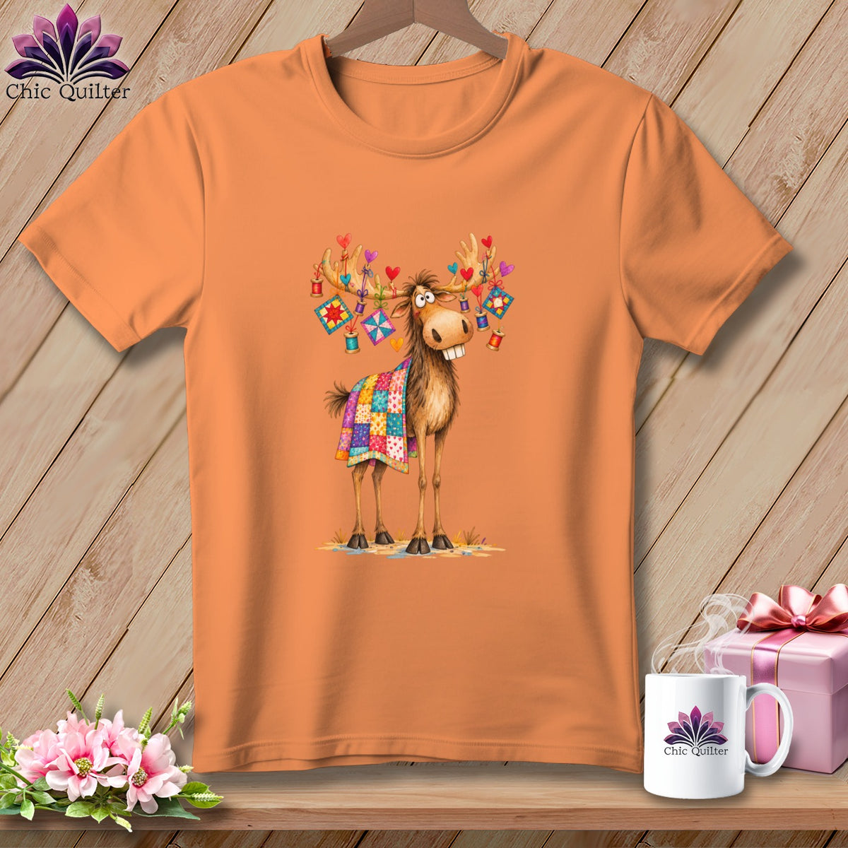 An orange t-shirt displays a cartoon moose with quilt pieces draped on its back and antlers.