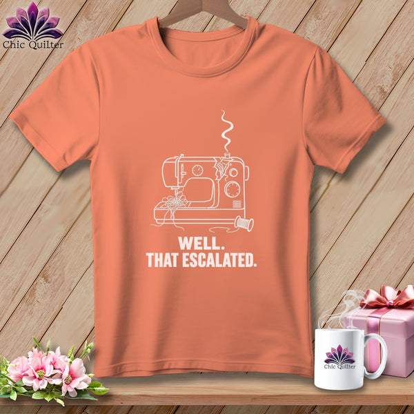 Coral t-shirt with a line drawing of a broken sewing machine and text reading "WELL. THAT ESCALATED."