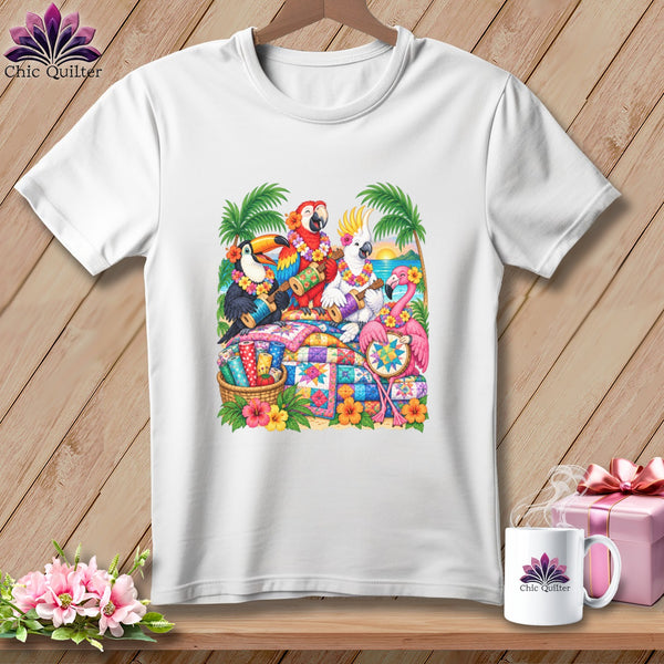 White short-sleeved t-shirt featuring a colorful graphic of tropical birds playing instruments atop patchwork quilts on a beach.
