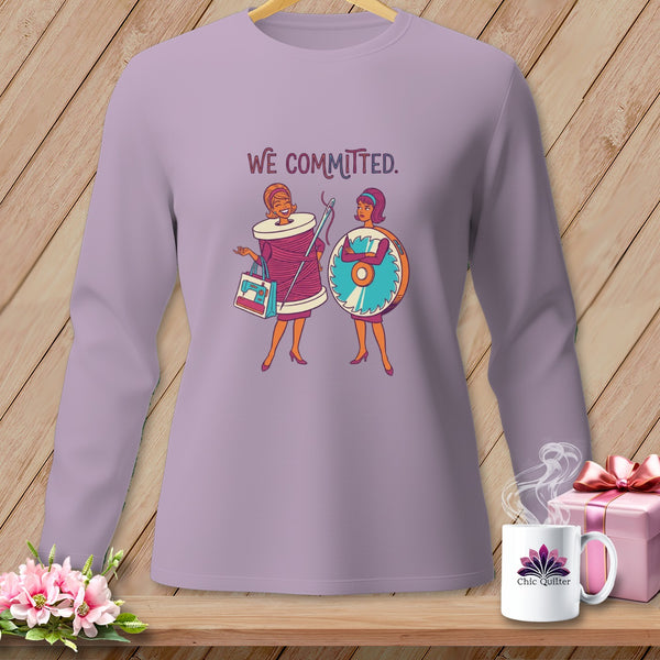 Lilac shirt with "WE COMMITTED" text and two cartoon women, one as a thread spool, one as a saw.