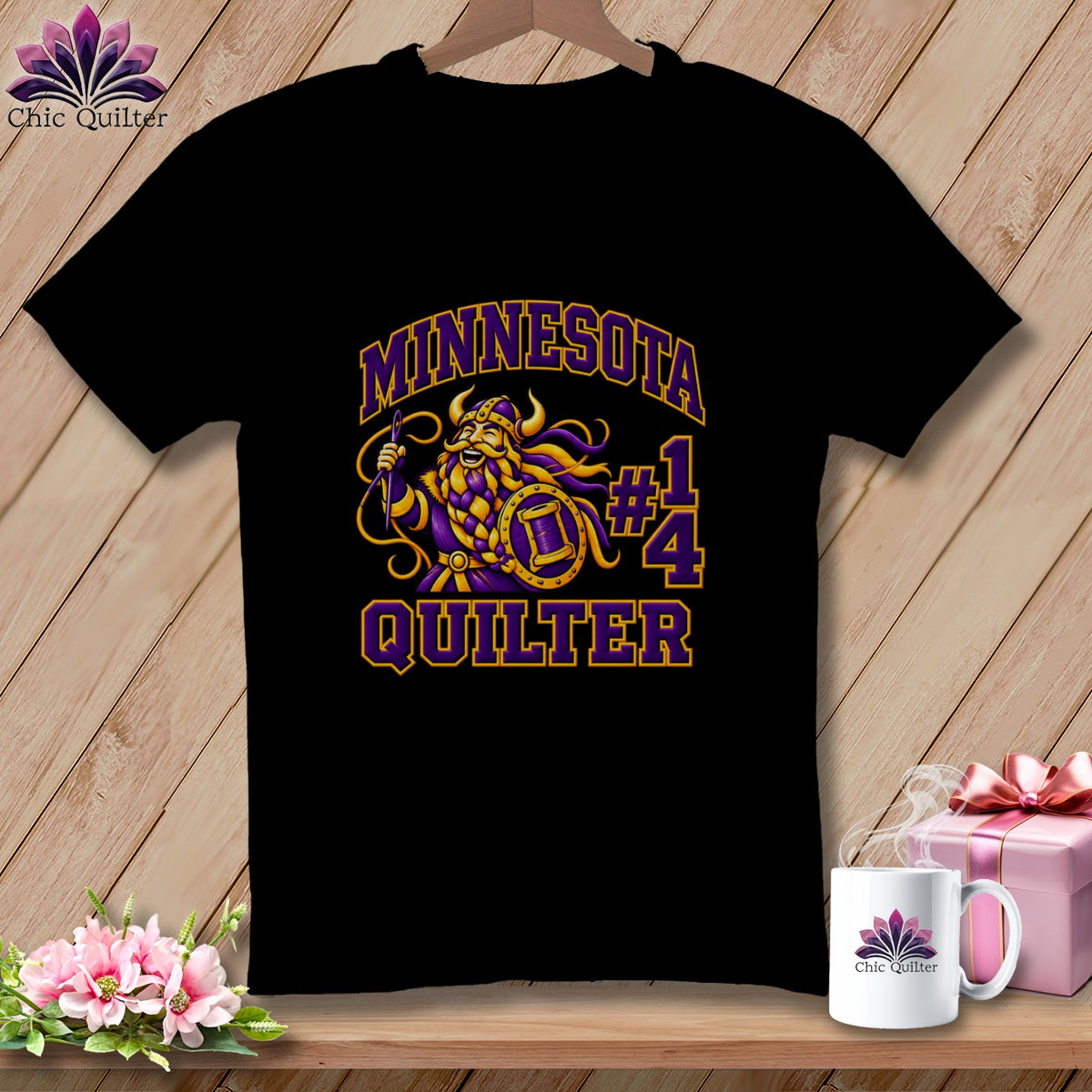 A black t-shirt hanging on a wooden background, featuring a graphic with a Viking, text "MINNESOTA QUILTER," and number 14.