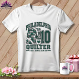 White t-shirt with a green graphic featuring a stack of quilts, the number 10, and text reading Philadelphia Quilter.