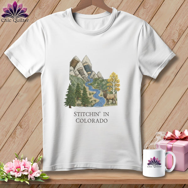 White t-shirt with "Stitchin' in Colorado" graphic featuring mountains, river, and elk.