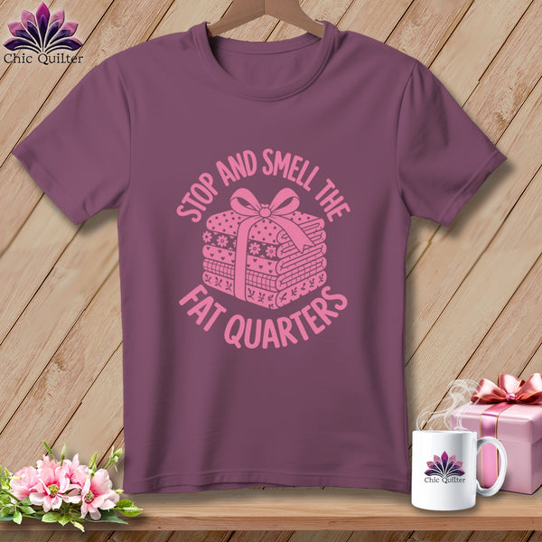 Purple t-shirt with pink graphic reading STOP AND SMELL THE FAT QUARTERS over a folded fabric bundle.