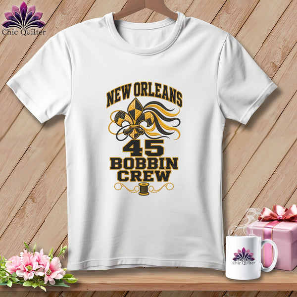 A white short-sleeved t-shirt featuring New Orleans 45 Bobbin Crew text with a fleur-de-lis design.
