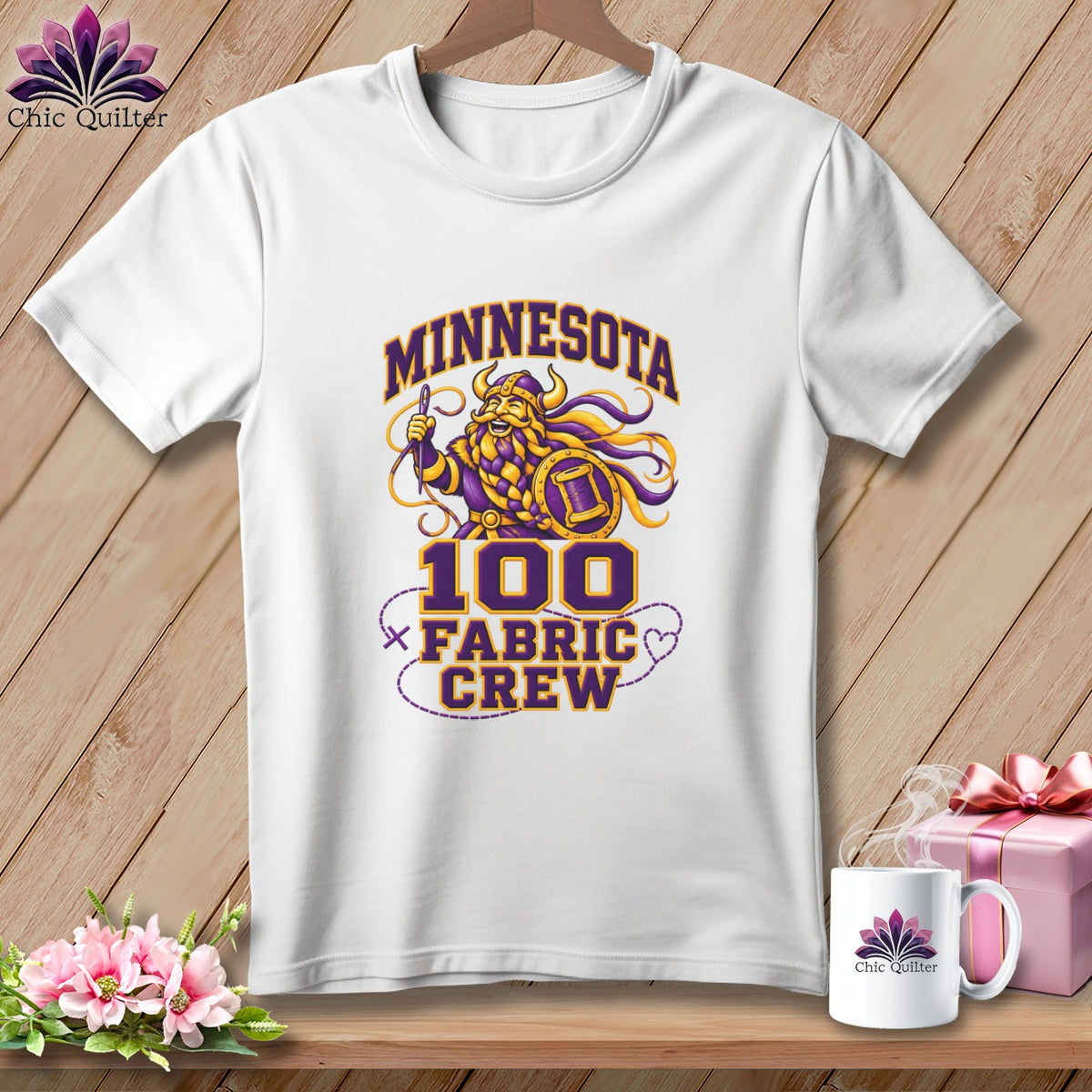 A white t-shirt features a purple and gold graphic with a Viking holding a needle.