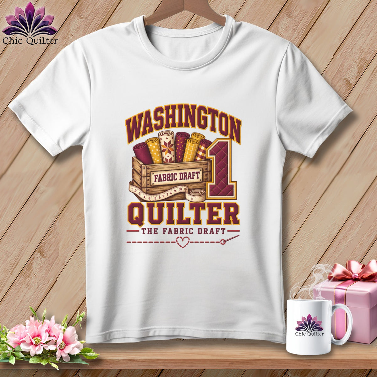 A white t-shirt featuring a Washington Quilter graphic with fabric bolts in a wooden crate.