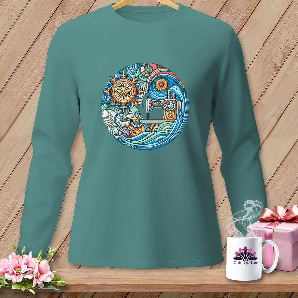 Teal long-sleeve shirt featuring a circular graphic of a sewing machine and sun.