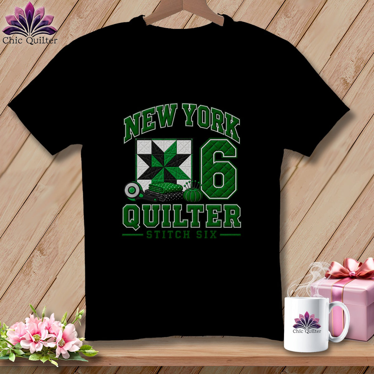 A black t-shirt hanging on a wooden background, featuring green text reading "New York Quilter Stitch Six" alongside a quilt block graphic and the number six.
