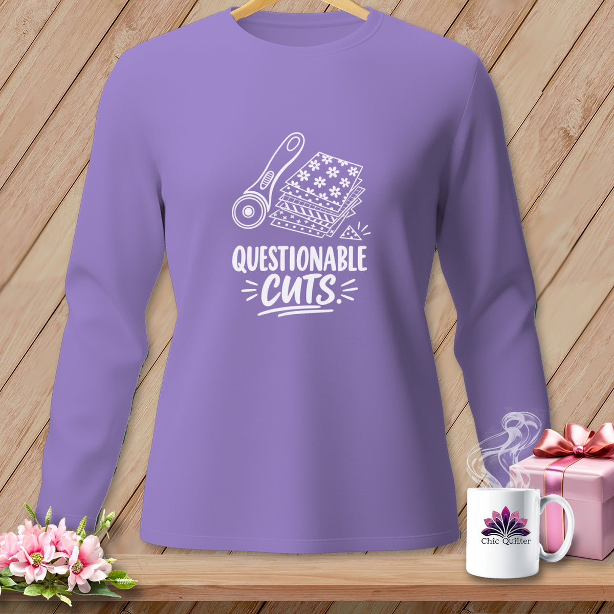 Purple long-sleeve shirt with white graphic "Questionable Cuts" and sewing tools.