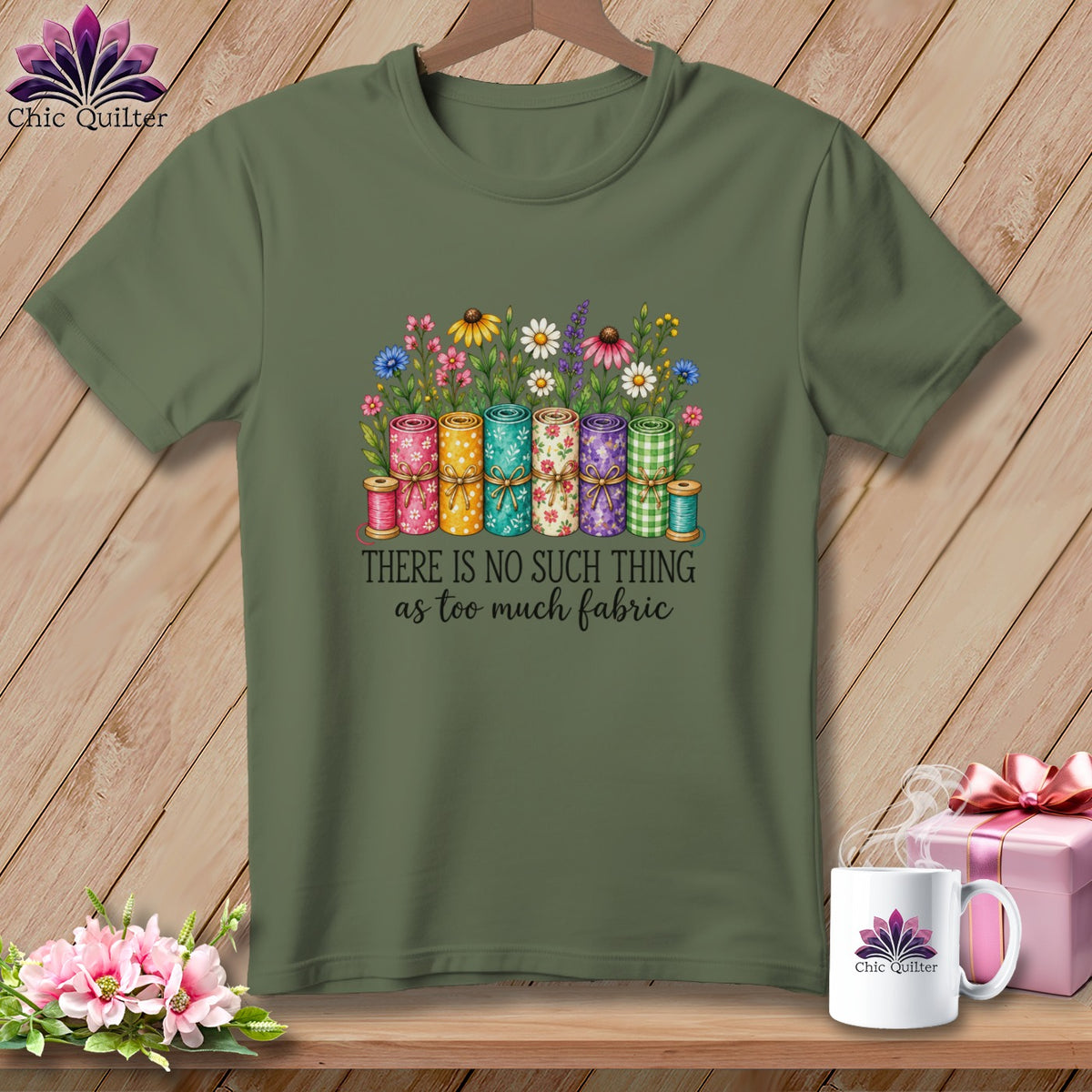 Olive green t-shirt with a graphic of fabric rolls, flowers, spools, and the text There is no such thing as too much fabric.