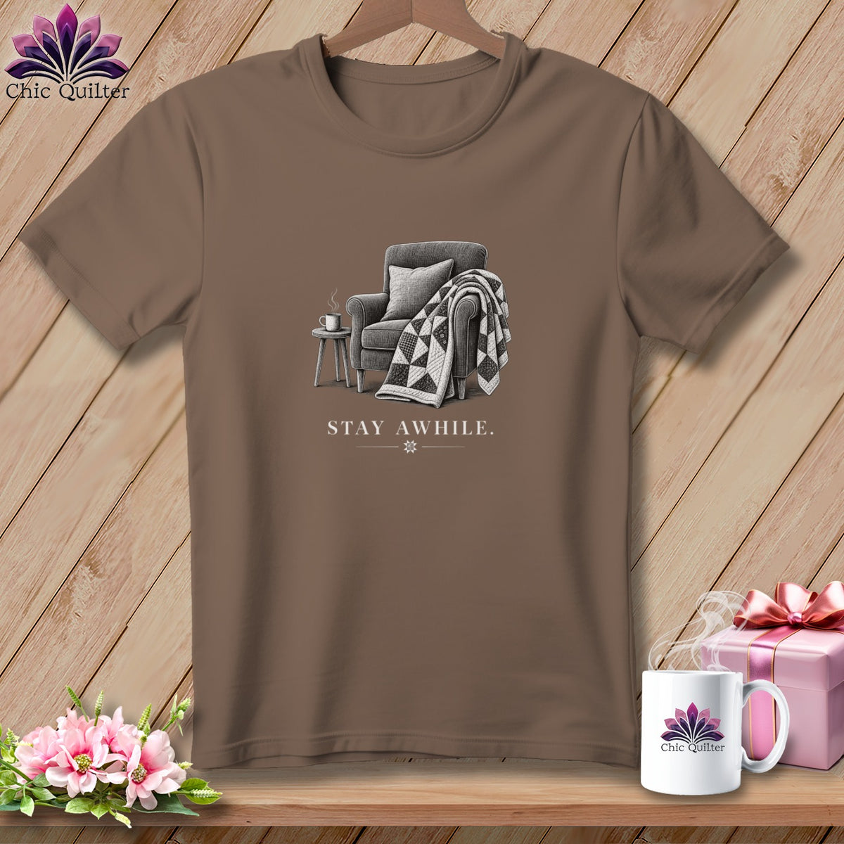 T-shirt with armchair, blanket, coffee, and "STAY AWHILE" text.