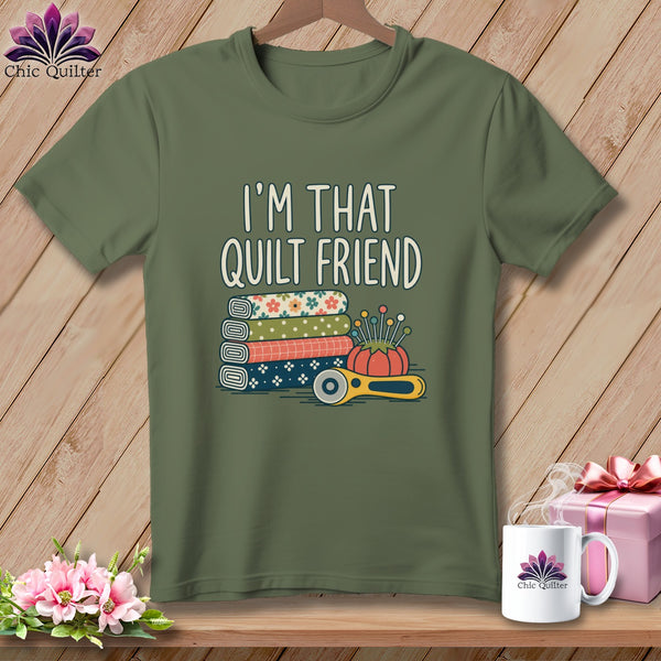 An olive green t-shirt with the text I'M THAT QUILT FRIEND above fabric rolls and a rotary cutter.