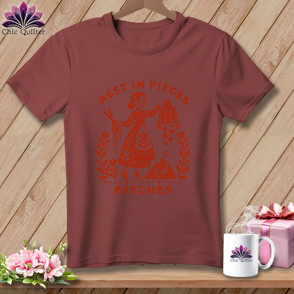 Maroon t-shirt with orange graphic of a woman with scissors and fabric, saying "Rest in Pieces Bitches".