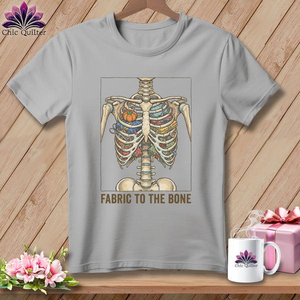 T-shirt with skeleton torso filled with fabric, scissors, and pumpkins, text "FABRIC TO THE BONE".