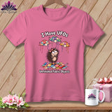 Pink t-shirt featuring a cartoon hedgehog, floating quilted UFOs, and the text I Have UFOs Unfinished Fabric Objects.