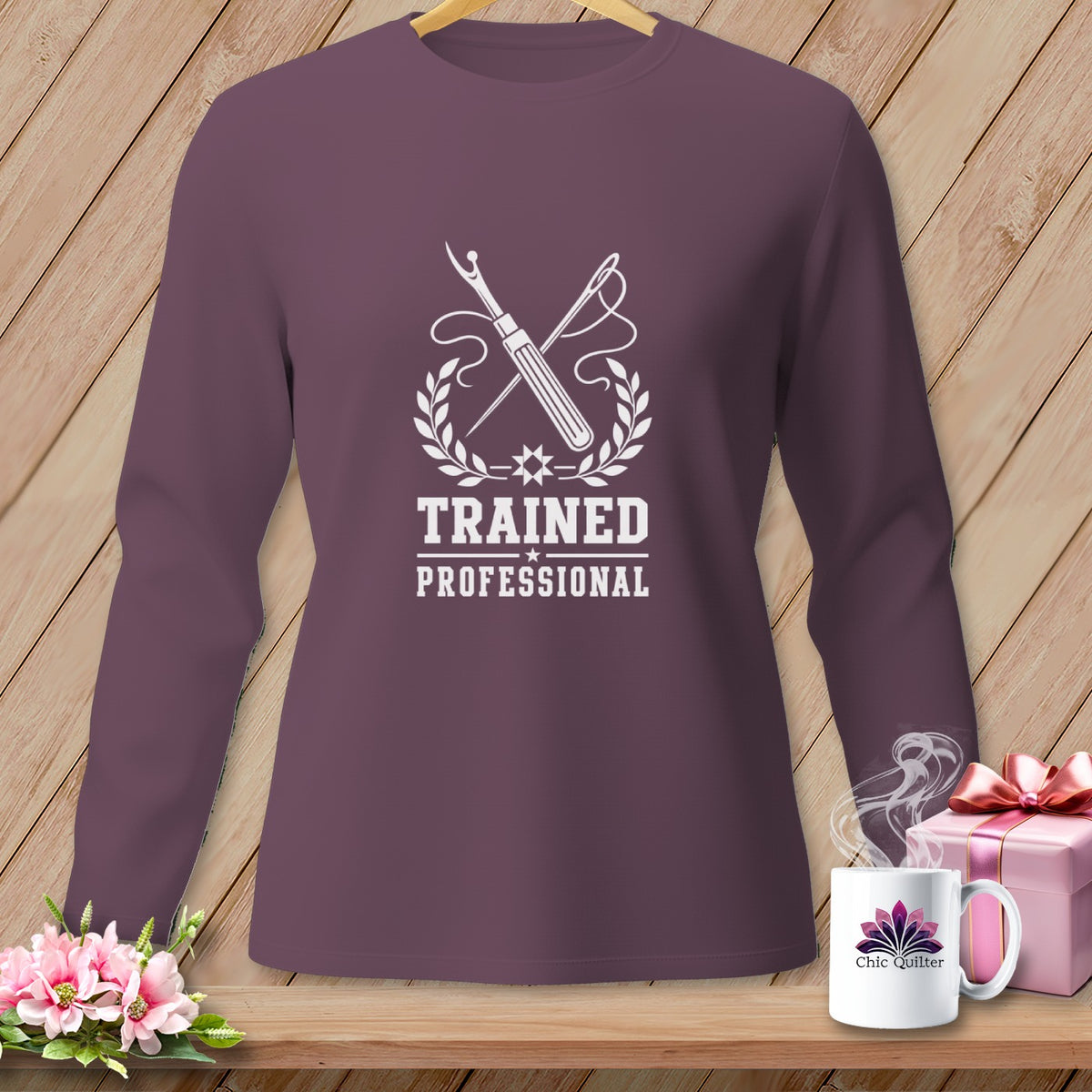 Long sleeve shirt with "Trained Professional" text, sewing tools, laurel wreath, and mug.