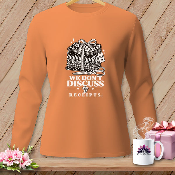 Orange shirt with graphic of fabric stacks, scissors, and "We Don't Discuss Receipts."