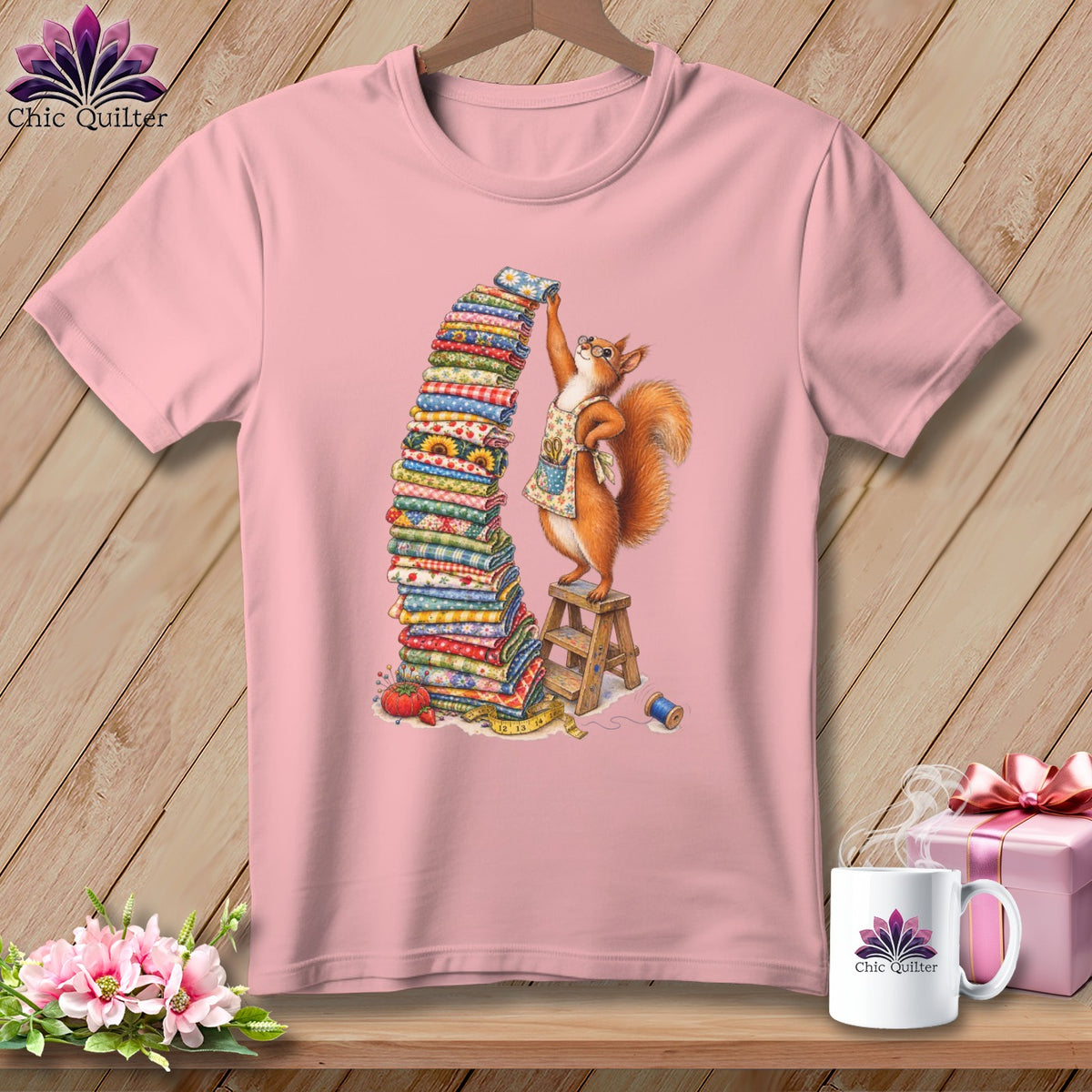 Pink t-shirt with a squirrel stacking colorful fabric on a wooden stool.