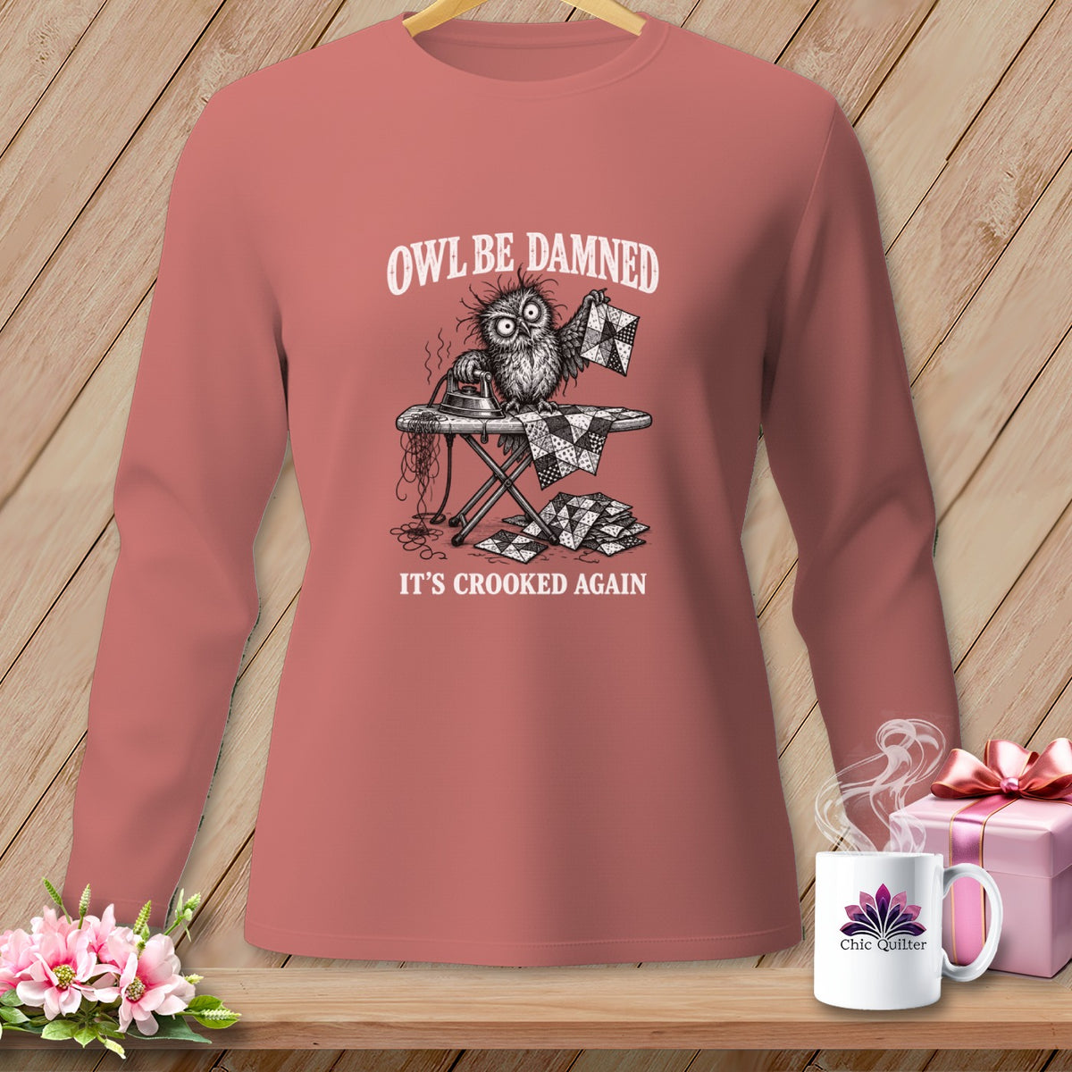 Long-sleeve shirt with a graphic of a distressed owl ironing a quilt, text "Owl Be Damned It's Crooked Again".