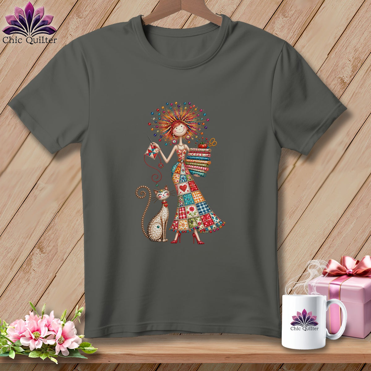 Dark gray t-shirt featuring a colorful cartoon graphic of a woman holding a quilt block and a stack of fabrics, alongside a cat.