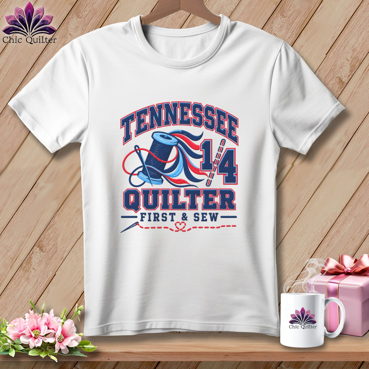 White t-shirt with a blue and red graphic featuring the text Tennessee Quilter First & Sew, a spool of thread, and a needle.