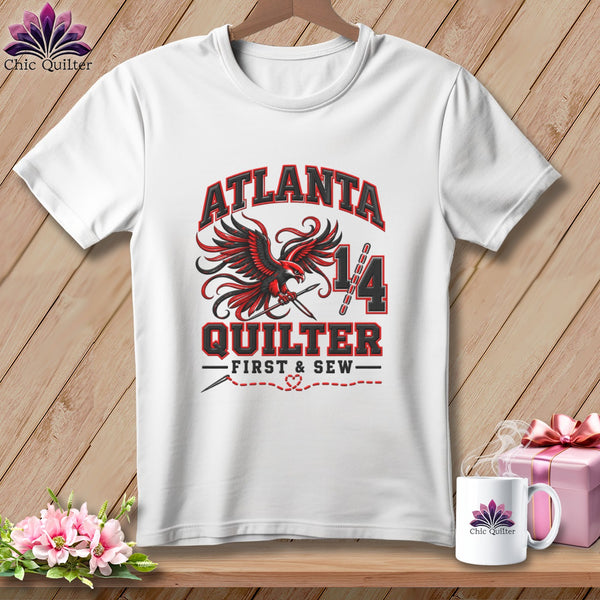 A white crew-neck t-shirt featuring red and black Atlanta Quilter graphic design with a soaring bird.