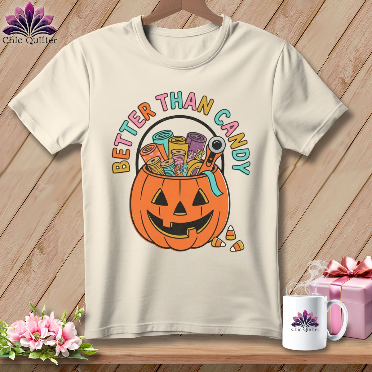 Cream t-shirt with a jack-o'-lantern bucket overflowing with colorful fabric rolls and sewing notions. Text reads "Better Than Candy."