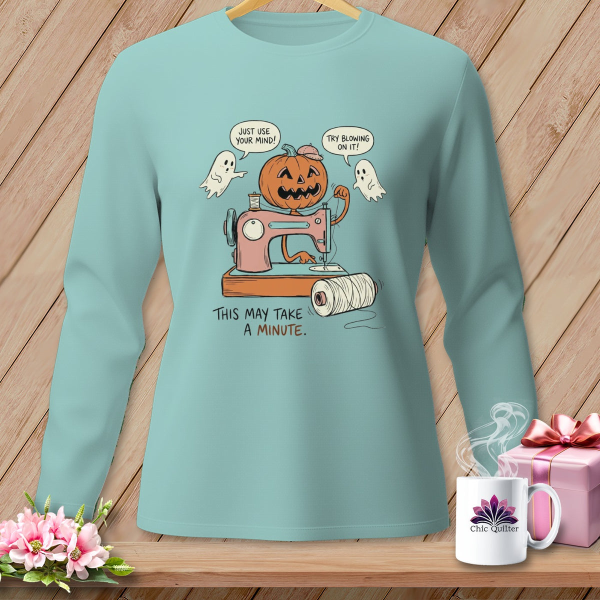 Long sleeve shirt with a Halloween-themed graphic of a pumpkin operating a sewing machine, with ghosts.