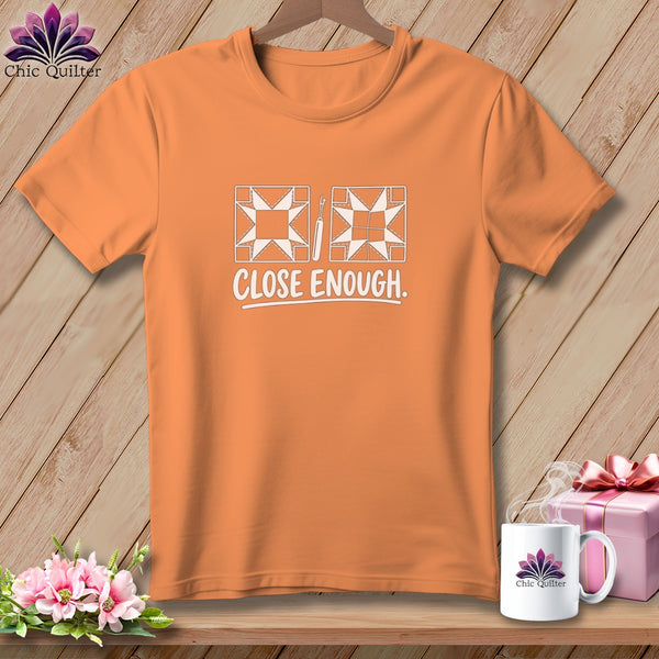 Orange t-shirt with quilt blocks, seam ripper, and text "CLOSE ENOUGH."
