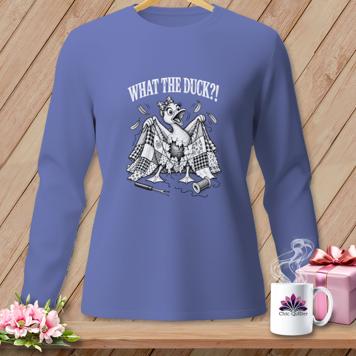 Periwinkle long-sleeved shirt with a graphic of a duck holding a quilt and text reading WHAT THE DUCK?!