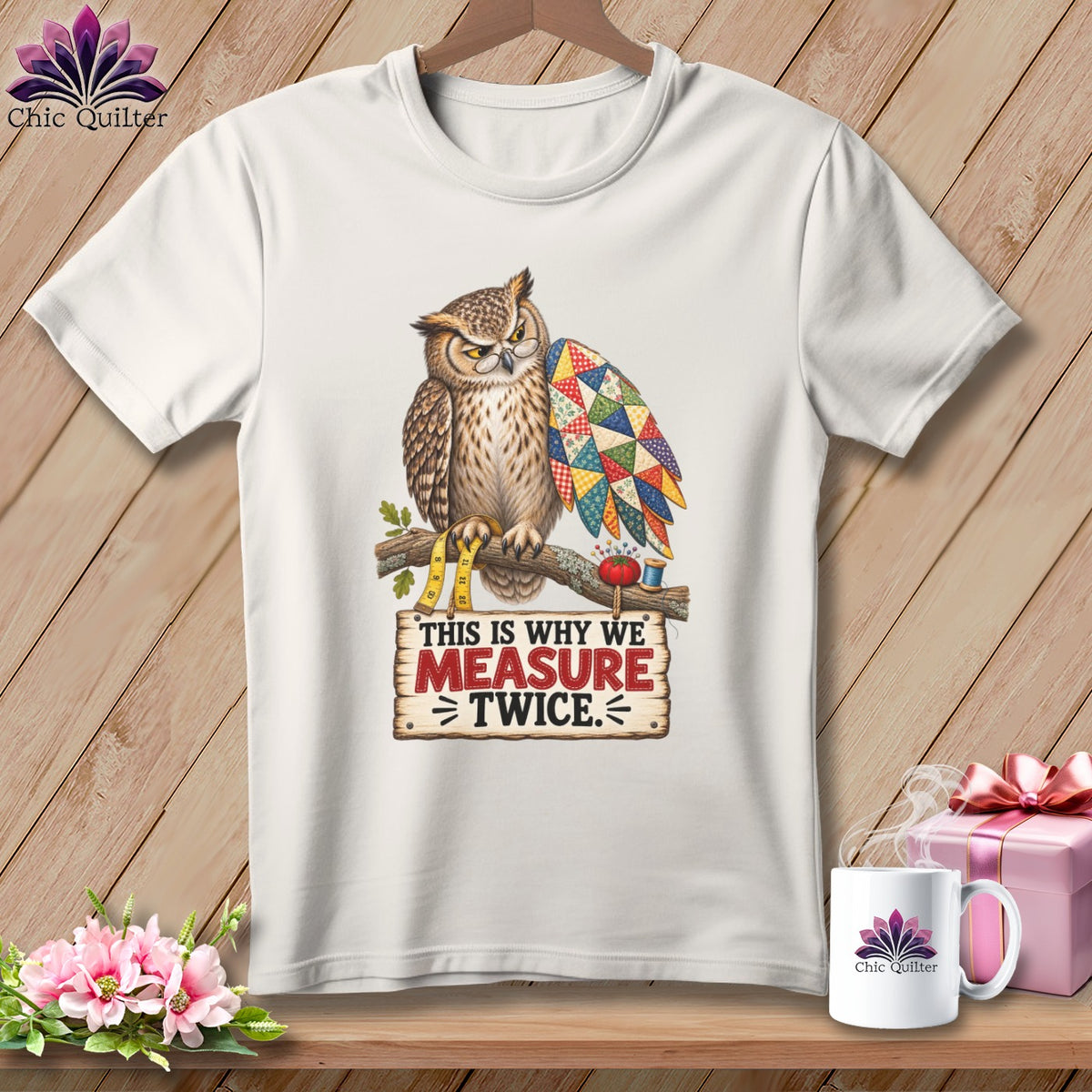 White t-shirt with an owl wearing glasses and a quilt-like wing, holding measuring tape.