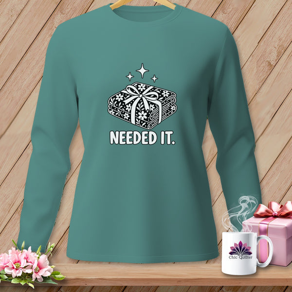 Teal long-sleeve shirt with a graphic of stacked fabric bundles and "NEEDED IT." text.