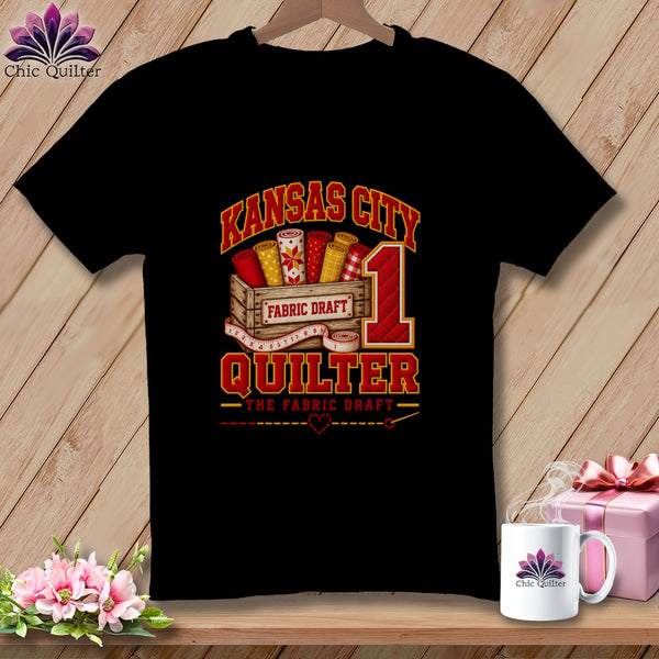 Black t-shirt featuring a Kansas City Quilter graphic with fabric bolts, wooden crate, and number one.
