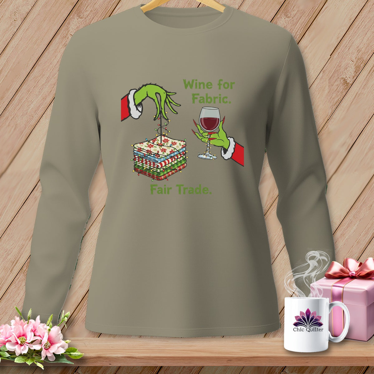 Green Grinch hands hold fabric and wine with text "Wine for Fabric. Fair Trade."