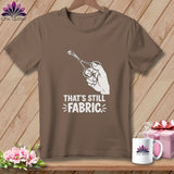 Brown t-shirt with white graphic of hand holding scissors cutting fabric and text 