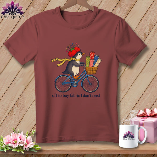 Penguin on bicycle with fabric rolls, wearing tomato hat with pins.