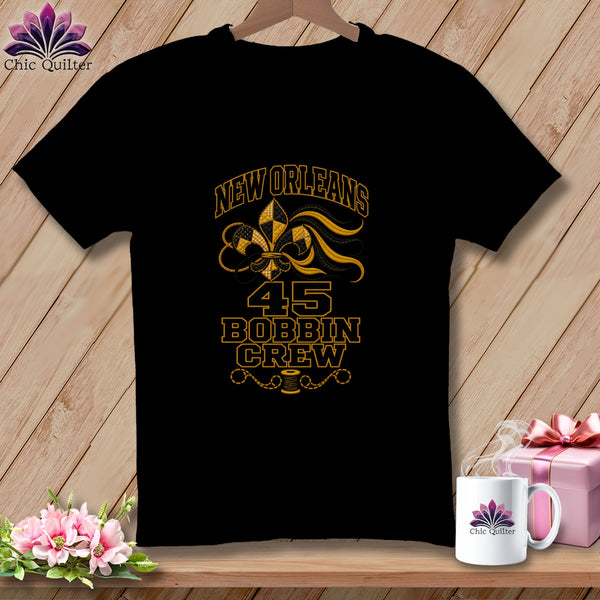 Black t-shirt featuring a New Orleans 45 Bobbin Crew design with a gold fleur-de-lis.