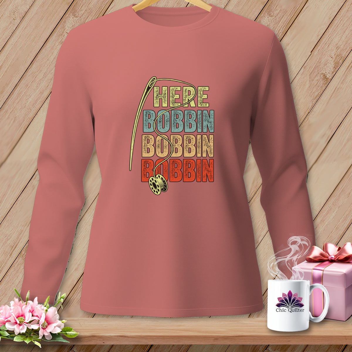 Long-sleeved pink shirt with "HERE BOBBIN BOBBIN" text and sewing needle graphic.