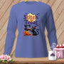 Black cat sewing with pumpkin, text "Stitch or Treat", on a purple long-sleeve shirt.