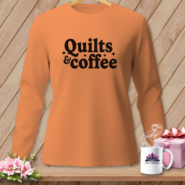 Orange long-sleeve shirt with "Quilts & coffee" graphic, next to a mug.
